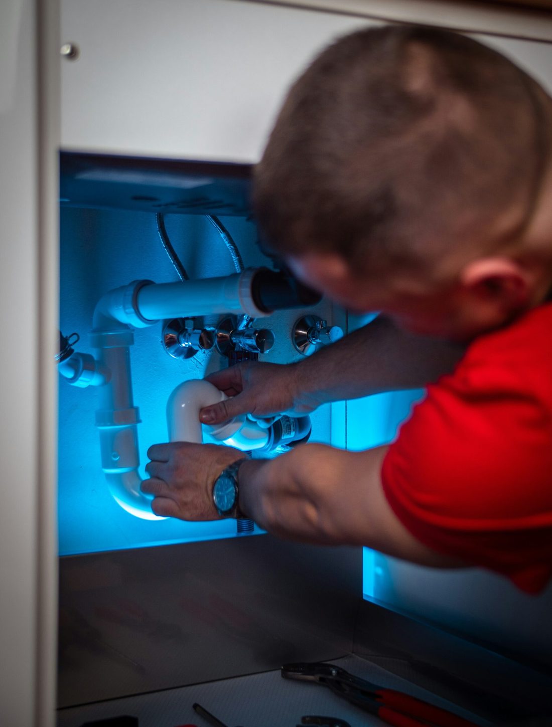 WA Property Services engineer fitting a waste trap under a kitchen sink