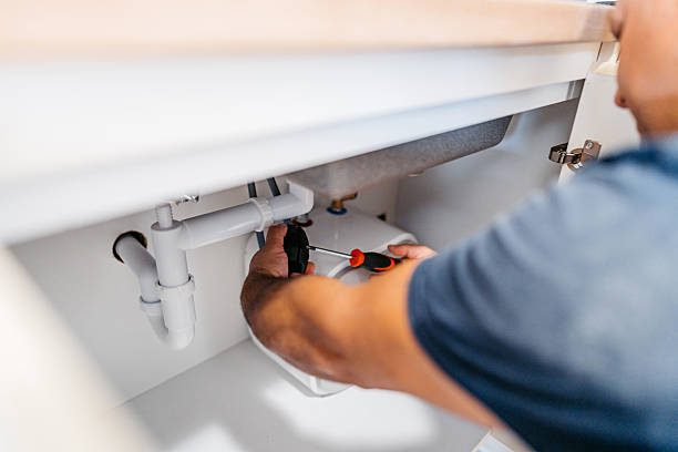 Plumber tightening a waste pipe under a bathroom basin